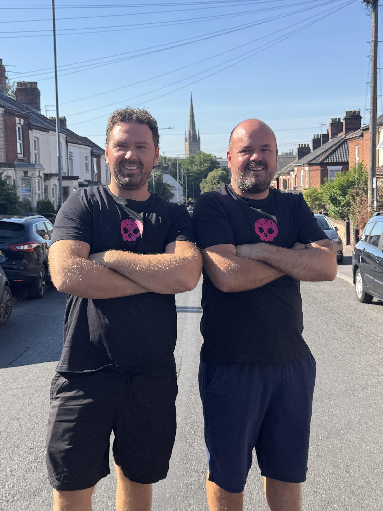 The two co-founders standing in the middle of a terraced residential street, with a cathedral spire in the distance.